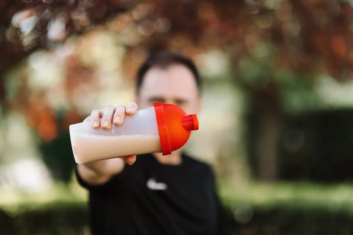 A man grips a pre-workout shake bottle, symbolizing his dedication to health and fitness.